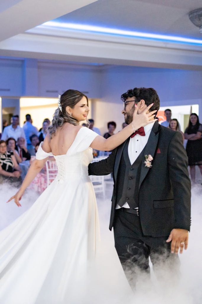 Bride and groom share a romantic dance surrounded by guests during their wedding reception.